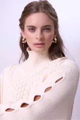 Sweater de punto color bordó con cuello alto y diseño de trenzas en el frente y las mangas. Presenta un corte holgado y largo, con puños y ruedo acanalados.