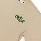 Remera de manga corta color beige, con cuello redondo y estampa pequeña en el pecho con el logo de la marca en color verde.