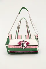 Bolso tote deportivo con diseño estampado en tonos blanco, verde y rosado, con detalles gráficos de tucanes y monograma central. Cuenta con doble asa de mano superior y correa ajustable para el hombro.