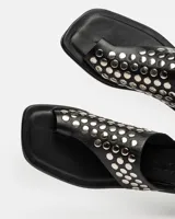 Sandalias planas blancas de cuero, con tira ancha sobre el empeine adornada con tachas plateadas.