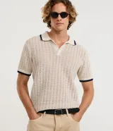 Camisa polo de tejido texturizado con efecto ganchillo, color beige, manga corta y cuello polo con detalles en color azul marino al igual que en los puños.
