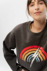 Buzo gris oscuro de algodón con felpa suave por dentro, cuello redondo y puños ajustados. Estampa frontal de arcoíris con un rayo blanco en el centro.