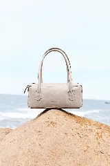 Cartera de cuero tipo baguette de Sagali, con formato alargado, acabado vintage y líneas minimalistas. Cuenta con dos asas largas para llevar al hombro y cierre superior.