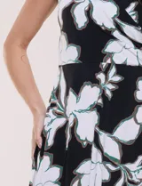 Vestido maxi sin mangas de seda fría, color negro con estampado floral blanco y verde. Presenta escote cruzado con detalle de abertura y corte en la cintura con falda amplia.