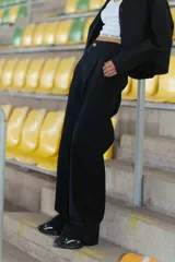 Pantalón negro de gabardina elastizada, corte sastrero, tiro bajo y pierna ancha. Tiene bolsillos delanteros, botón metálico con logo RENÉE y tajo en el lateral interno.