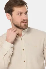 Camisa de lino color beige con cuello mao, manga larga, cierre frontal de botones y bordado sutil en el pecho.