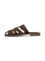 Sandalia plana estilo cangrejera color marrón chocolate, confeccionada en cuero gamuza, con diseño de tiras cruzadas y hebilla metálica dorada lateral.