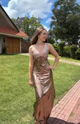 Vestido largo con estampado tie-dye en tonos violeta y fucsia, escote en V con detalles bordados dorados, cut-outs laterales bajo el busto y tirantes finos que se cruzan y atan en la espalda.