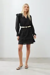 Vestido corto negro con escote en V, mangas largas abullonadas con puños elásticos, falda con volados y cinturón trenzado.