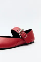Balerina roja de cuero sintético con punta ligeramente afilada y tira ancha con hebilla metálica.