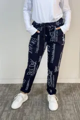 Babucha de corte holgado color azul marino con estampado de frases y letras blancas tipo graffiti. Presenta cintura elástica con cordón de ajuste, bolsillos laterales y ruedos con dobladillo.