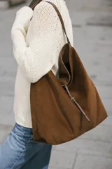 Bolso tipo shopper de textura acanalada efecto pana, color marrón. Cuenta con asa de hombro, cierre frontal con tira y hebilla metálica, y bolsillo interior con cremallera.
