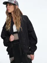 Campera tipo bomber color negro, con cierre frontal, cuello redondo, puños y ruedo elásticos, y bolsillos laterales con solapa.