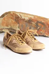 Zapatillas bajas color beige con cordones, capellada de tela y puntera de gamuza.