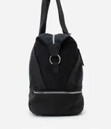 Bolso tipo maleta de tamaño grande en color negro, confeccionado en una mezcla de poliuretano y poliéster. Presenta cierres de cremallera plateados contrastantes, un bolsillo frontal con cierre y un compartimento inferior independiente con cierre. Incluye asas de mano dobles y una correa de hombro larga, ajustable y extraíble.