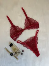 Conjunto de lencería de encaje rojo, compuesto por un bralette con cierre frontal y una tanga regulable con laterales finos.