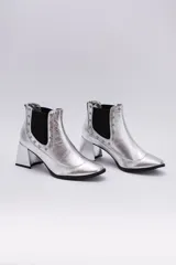 Botas Chelsea plateadas de cuero, con elásticos laterales negros, puntera fina y taco cuadrado.