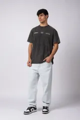 Remera negra con efecto acid wash, corte holgado y estampa frontal con logos y diseño de automovilismo.