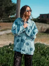 Campera celeste con lunares grandes color azul marino, con cuello camisero, cierre con botones a presión, bolsillos frontales con solapa y corte holgado.