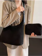 Bolso tipo hobo de material tipo gamuza o nobuk, color marrón camel. Presenta un diseño de silueta suave y caída, con una correa de hombro delgada de cuero liso del mismo tono.