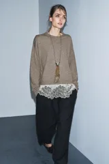 Jersey de punto color beige con cuello redondo y manga larga. Presenta un diseño de bajo combinado con un detalle de encaje en color crema.