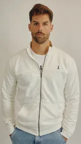 Campera de algodón color blanco con cierre frontal completo, cuello alto y bolsillos tipo canguro. Presenta un pequeño bordado en el pecho.