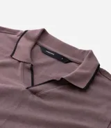Camisa polo de manga corta confeccionada en algodón, con cuello en V y detalles en color contrastante en el cuello y los puños. Presenta un diseño de tejido en media malla, ofreciendo una textura suave y transpirable.