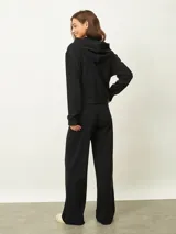 Campera negra con capucha, cierre frontal, mangas largas con puños elásticos y bolsillos laterales.