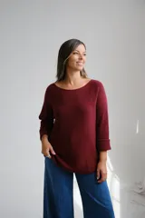 Sweter de punto color bordo, con escote a la base y mangas largas con puños doblados.