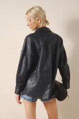 Camisa de cuero ovino color negro, de calce holgado y terminación arrugada. Tiene snaps metálicos color plata vieja con logo de la marca grabada.