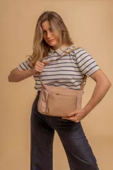 Bandolera de diseño práctico con combinación de texturas en tonos tierra, confeccionada en tela y símil cuero. Cuenta con un compartimento principal con cierre, un bolsillo frontal con cierre y correa ajustable para llevar al hombro o cruzada.