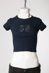 Baby tee de calce al cuerpo y manga corta, con cuello redondo y diseño con tachas frontales.