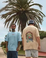 Remera celeste de manga corta con cuello redondo y estampado de tres hongos rojos con lunares blancos y la palabra 'Tuya' debajo.