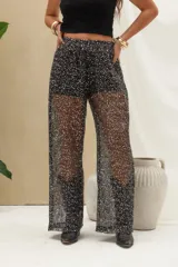 Pantalón largo negro con lentejuelas y acabado brillante, de corte recto y tejido semitransparente.