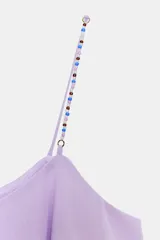 Top lila de corte holgado con diseño de múltiples volantes horizontales. Presenta escote redondo y tirantes finos decorados con abalorios multicolores.