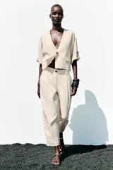 Chaqueta corta de escote en pico con cierre frontal de un botón. Presenta mangas cortas con detalle de vuelta, trabilla y botón, además de falsos bolsillos delanteros con solapa.