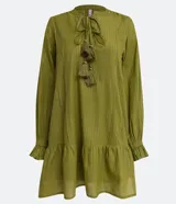 Vestido corto de manga larga en color verde oliva, confeccionado en tejido plano con hilos metalizados a contraste. Presenta cuello redondo con lazo decorativo y flecos, mangas largas con puños elásticos y detalle de volados en los puños.