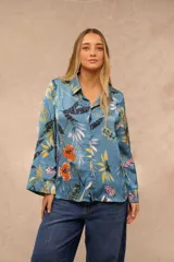 Camisa de satén azul con estampado botánico y floral en tonos amarillos, naranjas y blancos, de manga larga y cierre frontal con botones.