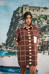 Vestido camisero corto marrón con estampado a cuadros blancos y bolsillo en el pecho.