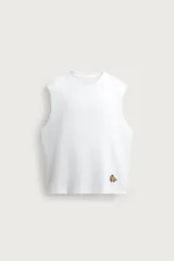 Camiseta sin mangas tipo tank top de corte relaxed fit, color blanco, con cuello redondo y detalle de bordado de plátanos en la parte inferior frontal.