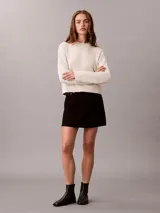 Sweater Calvin Klein de punto color blanco, de corte regular y manga larga, con cuello redondo y el logo de la marca en relieve en el pecho. Cuenta con puños y dobladillo acanalados.