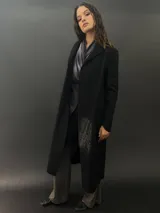 Tapado largo de paño de lana color negro con estampado abstracto brillante en el frente. Tiene cuello con solapas, bolsillos laterales y terminación al tallo vivo.