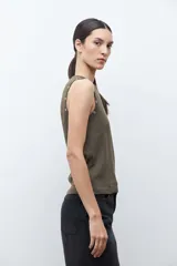 Top sin mangas color verde oliva, con cuello redondo y detalle de ojalillos metálicos a lo largo de los hombros.