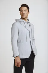 Blazer sport color gris claro con capucha integrada y cordones ajustables. Presenta solapas clásicas, cierre frontal con botones y bolsillos laterales de parche.