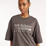 Remera New Balance de algodón gris oscuro con cuello redondo y mangas cortas. Presenta un diseño de corte holgado y estampado gráfico bordado en el pecho con las inscripciones "New Balance Athletics".