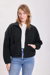 Campera de polar negro con cierre frontal, cuello alto, bolsillos laterales y corte holgado.
