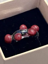 Anillo artesanal de vidrio transparente con diseño irregular y esferas de vidrio color bordó integradas en la estructura.