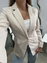 Blazer sastrero de corte clásico en color beige, con solapas tradicionales, cierre frontal de un botón y bolsillos laterales con solapa.