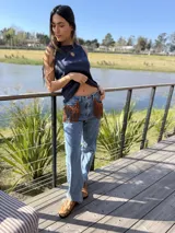 Jeans tiro medio de corte recto y calce holgado, color azul claro. Cuenta con bolsillos delanteros decorados con flecos de gamuza marrón.