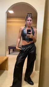 Top negro de cuero sintético con escote halter y cierre frontal con cremallera.